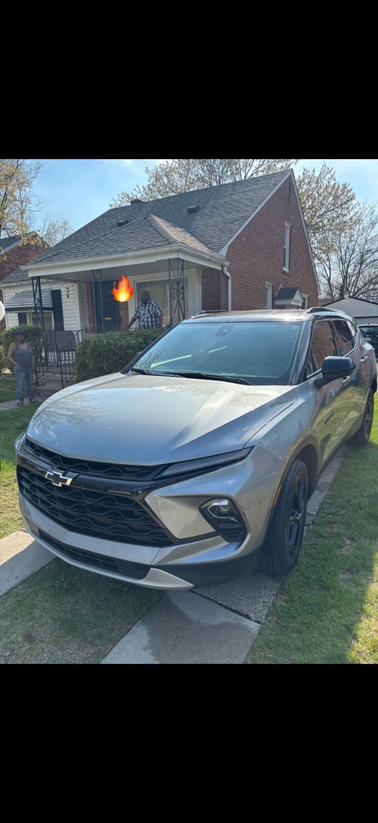 Silver Chevrolet Blazer parked on residential driveway in front of brick house with bare spring trees