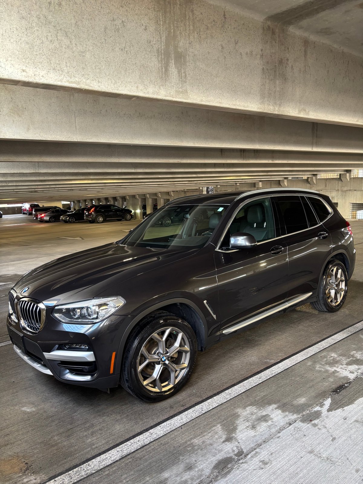 Black BMW X3 luxury SUV parked in an underground garage with concrete pillars